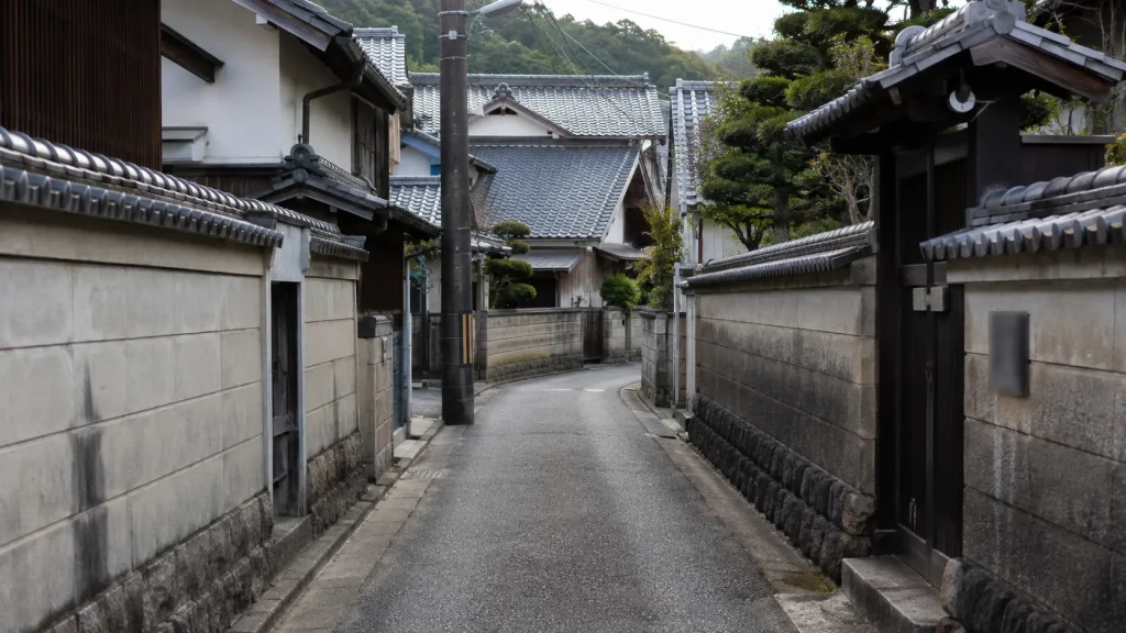 車がやっと通れる幅の古い住宅地の道路のイメージ