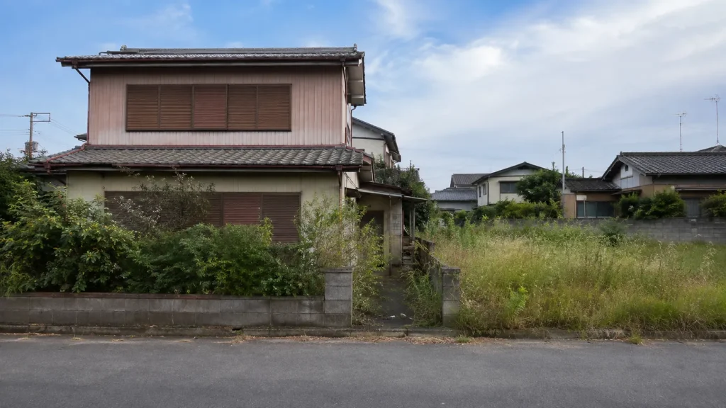 長く空き家になっている木造住宅と、隣接する空き地のイメージ