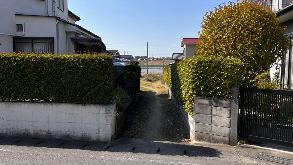 生垣にはさまれた細い土の道。敷地の脇を通る里道の例